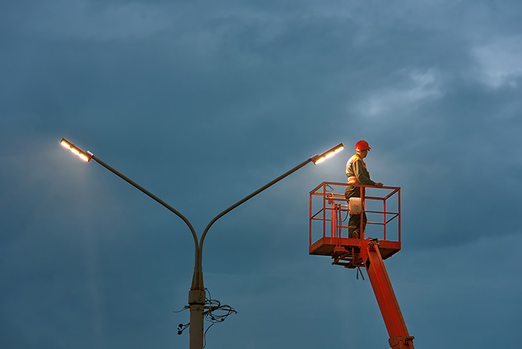 Electrician using bucket truck to fix outdoor lighting