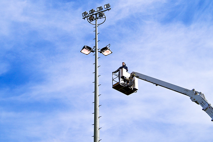 Electrical technician fixing outdoor lighting with a bucket truck