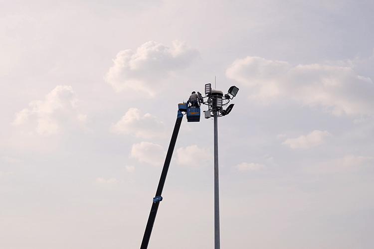 Electrical service technician adjusting hard to reach lights with a bucket truck